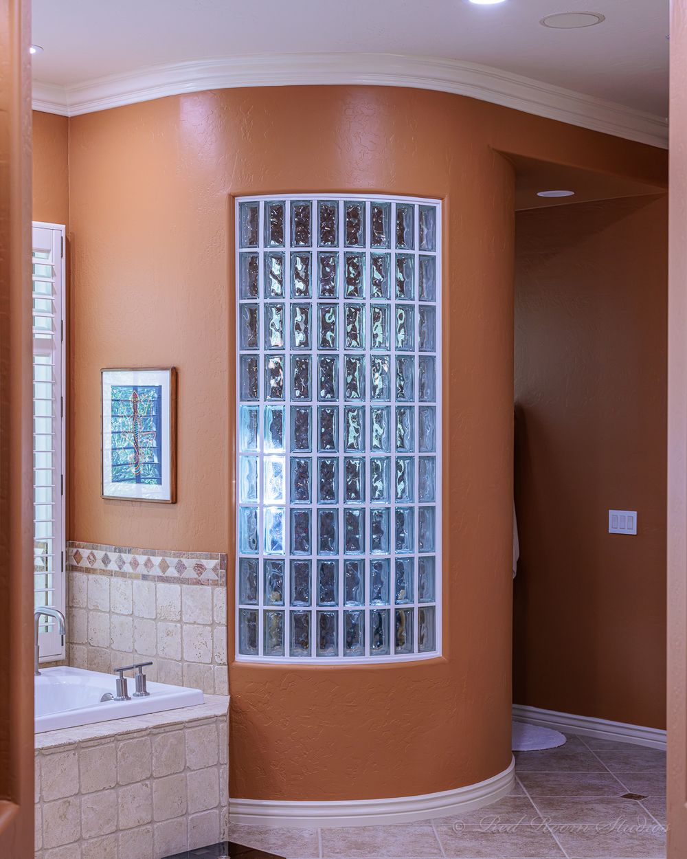 Curved Phoenix bathroom wall finished in warm terracotta beside a glass block window