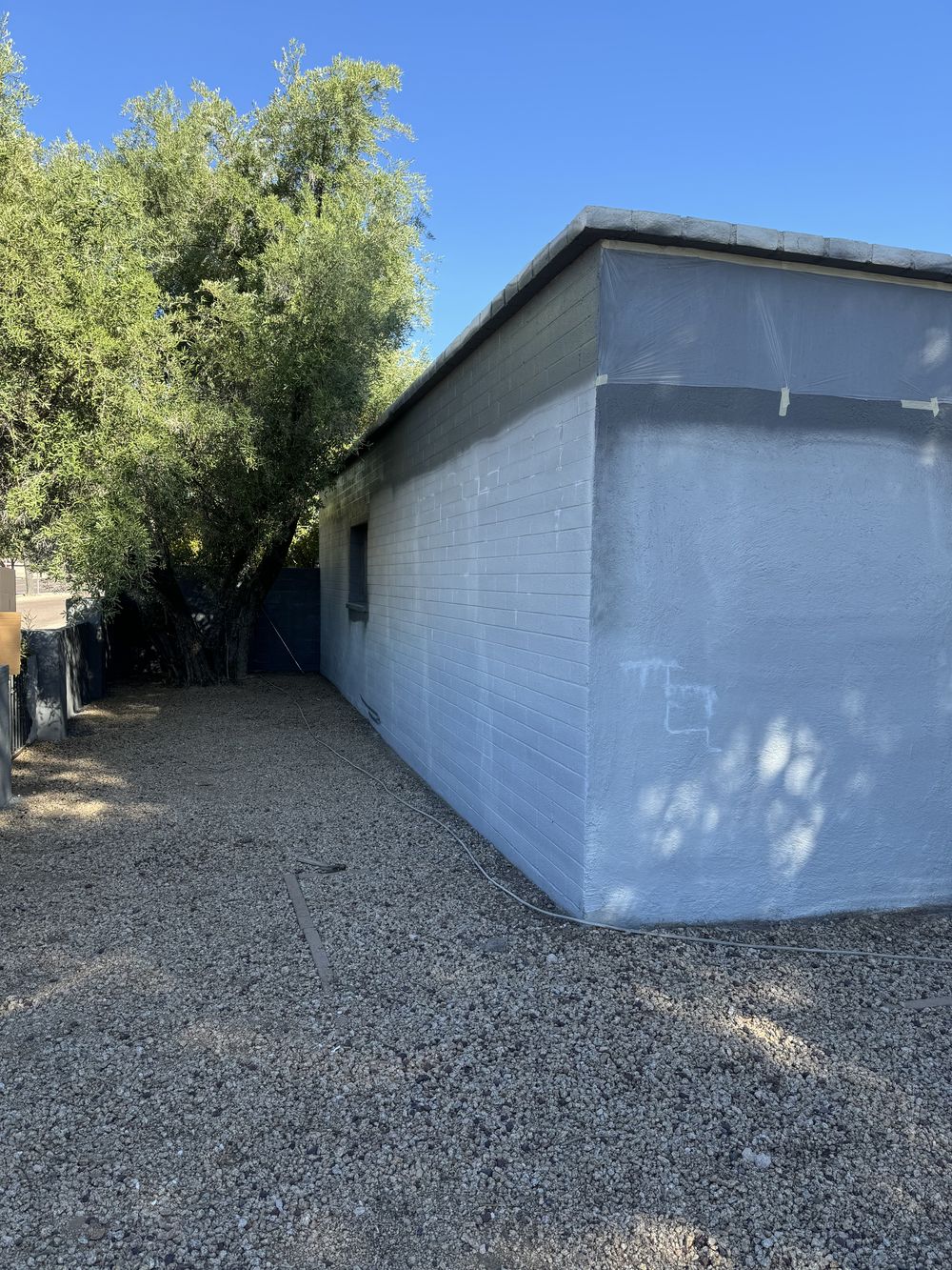Block wall in fresh grey primer with the roofline masked in plastic