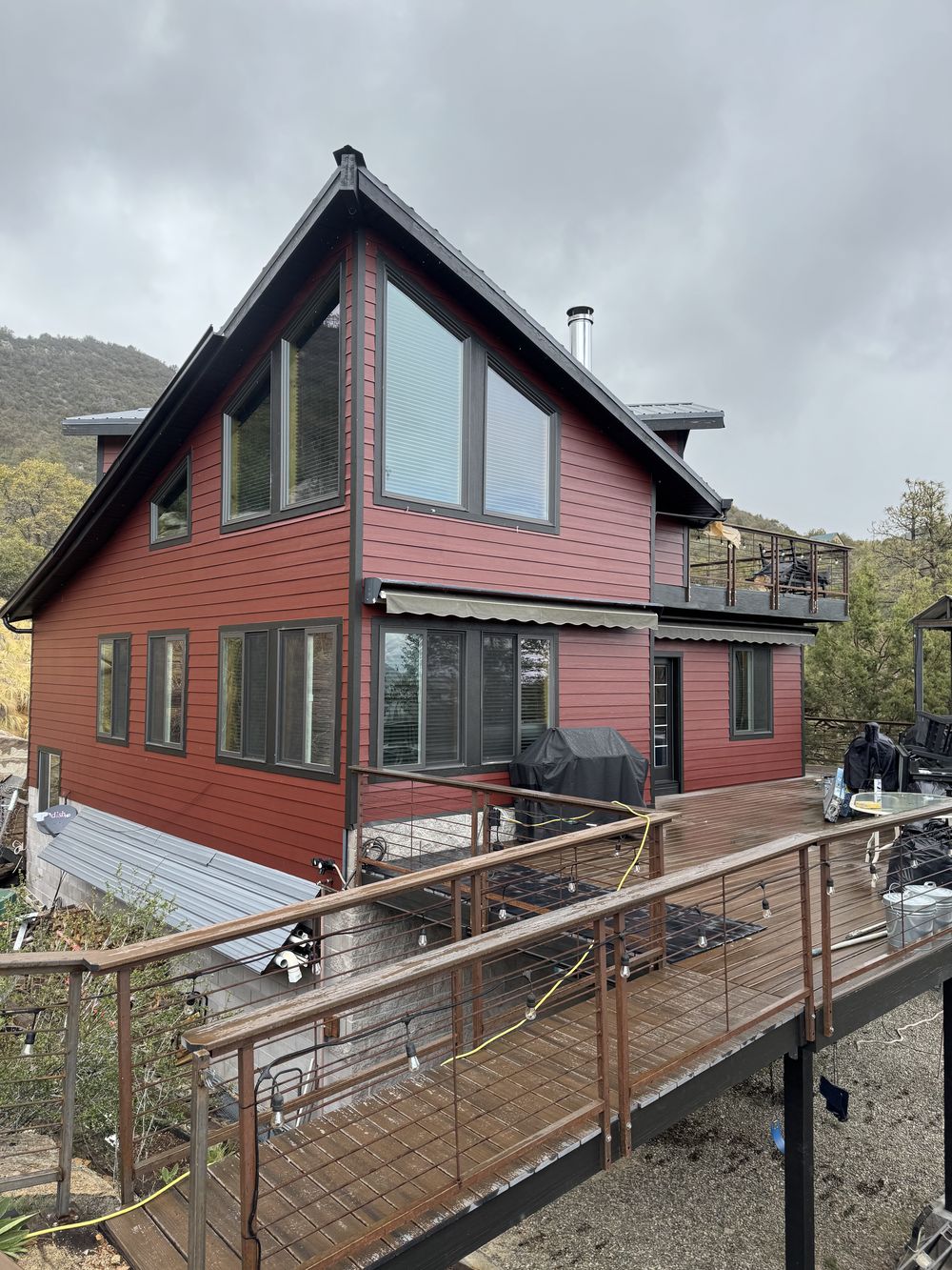 Arizona mountain cabin refinished in barn red with dark bronze window trim and a stained deck