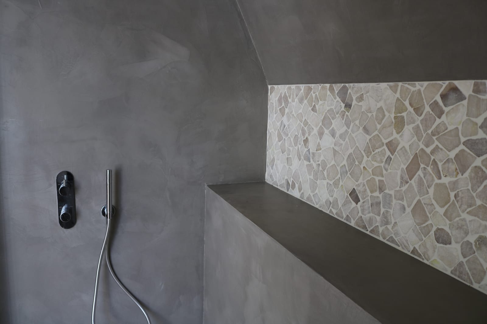 Seamless grey microcement shower enclosure with a formed bench, no grout lines or joints in the surface