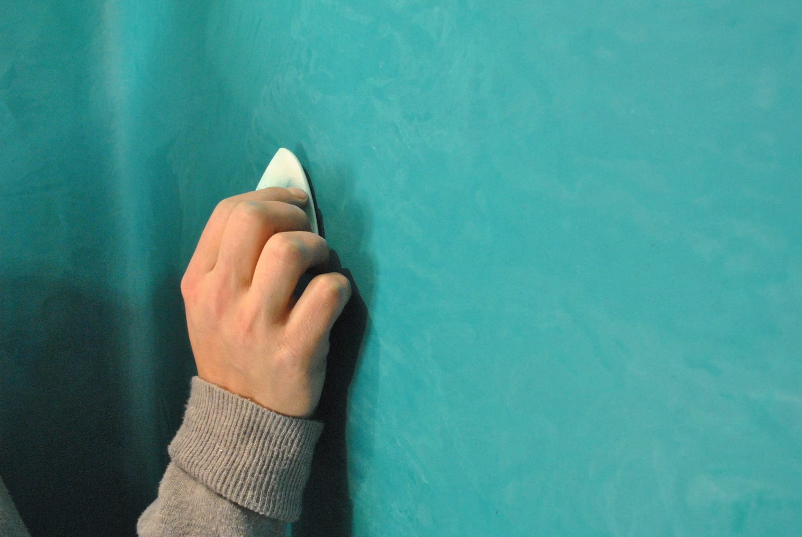 Lime plaster being compressed by hand with a burnishing stone