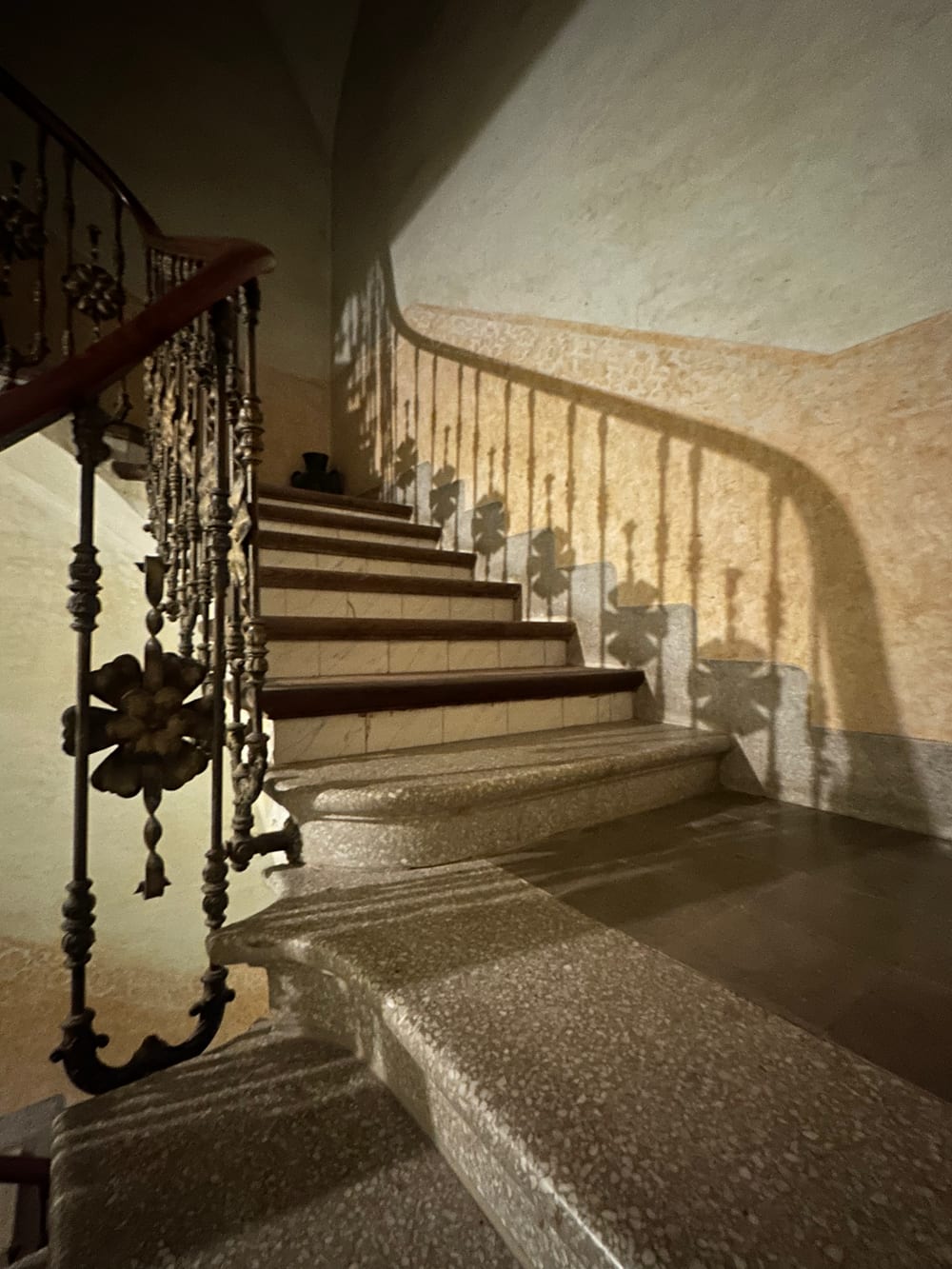 Burnished lime plaster wall curving around a stairwell, raking light picking out the polish and the trowel movement